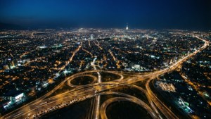 城市的夜間航拍視圖，有照明的高速公路和一座高塔。