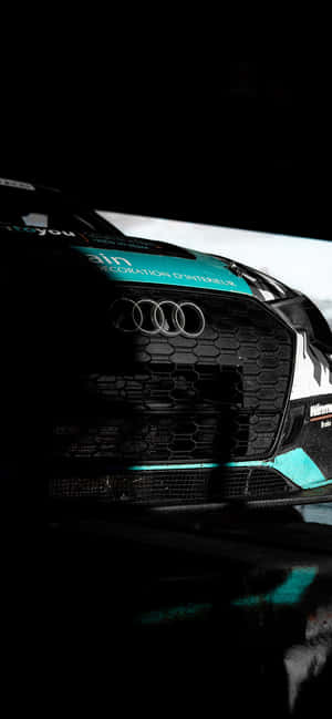 Audi 賽車前格柵特寫，帶有青綠色點綴和碳纖維紋理。 — iPhone 12 mini 壁紙