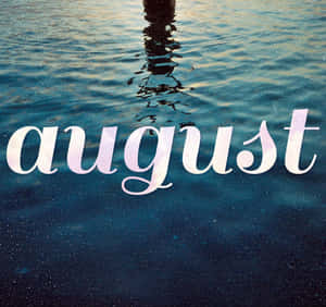 「august」這個字用白色字體寫在泛起漣漪的藍色水上面，還有一個人的倒影。 — 八月 壁紙
