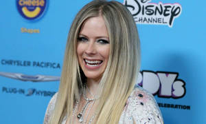 Avril Lavigne 在迪士尼頻道活動中微笑，身後有贊助商標誌。 — 艾薇兒·拉維尼 壁紙