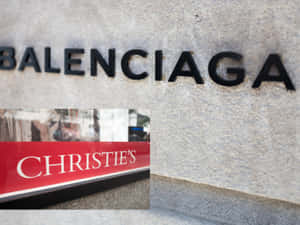 Balenciaga 和 Christie's 標誌在石建築外牆上，帶有窗戶反射。 — 巴黎世家 壁紙
