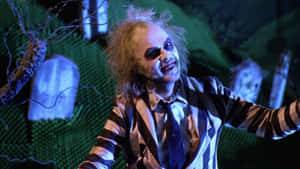 Beetlejuice 穿著條紋西裝在墓地場景中咧嘴笑 — 陰間大法師 壁紙
