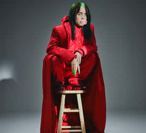 Billie Eilish 身穿紅色服裝在木凳上吹粉紅色泡泡糖泡泡。 — 怪奇比莉 GIF 壁紙