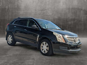 黑色 Cadillac SRX SUV 停放在灰色混凝土牆前。 — 凱迪拉克 壁紙