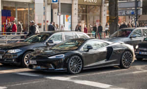 黑色McLaren跑車在繁忙的城市街道上行駛，有行人。 — 福特 壁紙