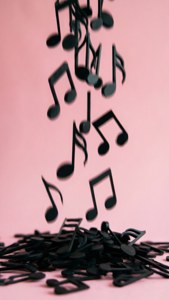 黑色音符以動態抽象排列落在粉紅色表面上。