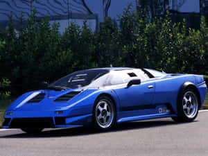 藍色Bugatti EB110超級跑車停在路上，背後有綠色灌木叢。 — 布加迪 GIF 壁紙