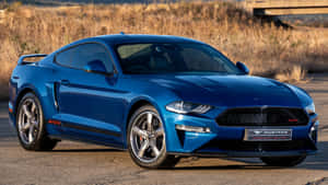 日落時分，藍色福特Mustang GT500停放在鋪砌的道路上。 — 16:9 壁紙