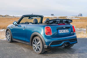 藍色MINI Cooper Convertible停泊在雪地附近的碎石路上。 — Surface Pro 壁紙