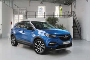 藍色Opel Grandland X SUV在一個明亮的白色工作室中，有樓梯和窗戶。 — MacBook Pro M3 壁紙