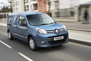 藍色雷諾 Kangoo 廂型車在街道上行駛，帶有動態模糊效果。 — Surface Pro 壁紙