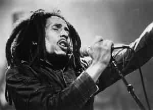 Bob Marley 在舞台上充滿激情地對著麥克風唱歌。 — 巴布·馬利語錄 壁紙