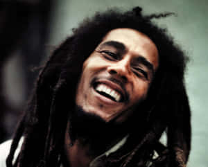 Bob Marley 帶著他標誌性的辮子和燦爛的笑容大笑。 — 巴布·馬利語錄 壁紙