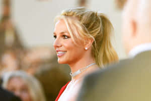 Britney Spears 在正式活動中穿著紅色連衣裙和鑽石頸鏈微笑。 — 小甜甜布蘭妮 壁紙