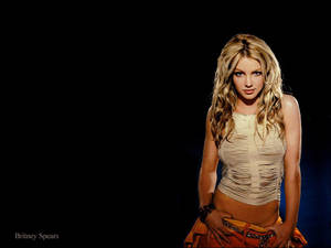 Britney Spears 身穿破爛的米色上衣和橙色裙子，背景為黑色。 — 小甜甜布蘭妮 壁紙