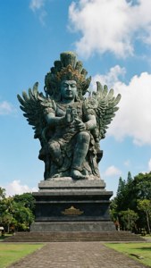 藍天下，一座帶翅膀、多臂神祇的大型青銅雕像。