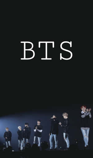 七位 BTS 成員在舞台上，聚光燈下，上方有「BTS」文字。 — Tecno Megapad 壁紙