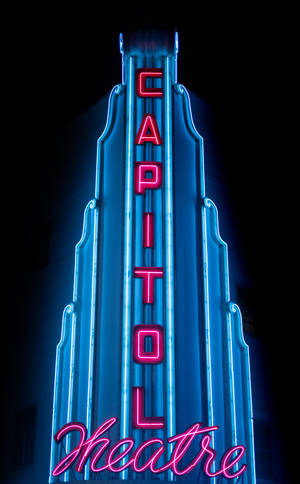 Capitol Theatre 的霓虹招牌在夜晚以藍色和粉紅色燈光閃耀。 — Moto Pad 70 Pro 壁紙