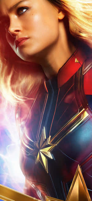 Captain Marvel 穿著她的超級英雄戰衣，帶有發光的能量效果。 — iPhone 16 Pro 壁紙