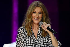 Celine Dion 在舞台上微笑著拿著麥克風。 — 席琳·狄翁 壁紙