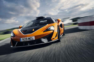 橙色McLaren賽車在賽道上奔馳，帶動態模糊效果 — MacBook Air M4 壁紙