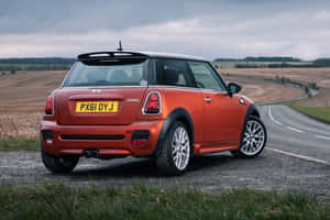 橙色Mini Cooper S停泊在鄉村道路旁的碎石上。 — 超跑 壁紙
