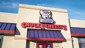 Chuck E Cheese's restaurant with mascot sign and blue sky — 查克芝士 壁紙