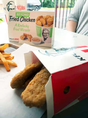 KFC Beyond Fried Chicken 盒裝雞柳和薯條放在桌上。 — 肯德基 壁紙