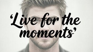 有鬍鬚和造型頭髮的男子，在勵志文字「Live for the moments」後方。