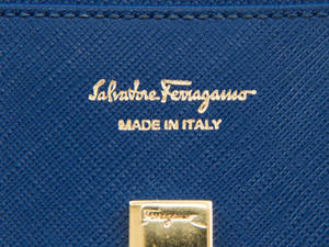 藍色皮革錢包特寫，帶有金色 Salvatore Ferragamo 標誌和扣。 — 薩瓦托雷·菲拉格慕 壁紙