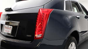 黑色 Cadillac 轎車尾部視圖，帶紅色尾燈和鍍鉻飾條。 — 凱迪拉克 壁紙