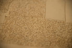 古老手寫文字在羊皮紙上的特寫，帶有溫暖的燈光。 — Old Paper 壁紙