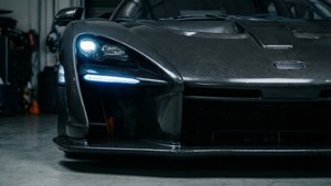 車庫中車頭燈亮起的黑色碳纖維跑車。