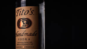 深色背景下的 Tito's Handmade Vodka 酒瓶標籤 — 品牌 壁紙