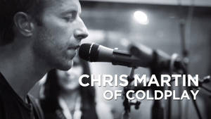 Coldplay 的 Chris Martin 在錄音室中對著麥克風唱歌。