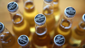 一組 Corona Extra 啤酒瓶，銀色瓶蓋，置於木桌上。 — 精細 壁紙