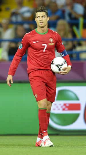 Cristiano Ronaldo 身穿葡萄牙紅色球衣，夜間在球場上手持足球。 — 克里斯蒂亞諾·羅納度 壁紙