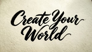 在帶有紋理的紙上以黑色刷字體手寫的勵志短語「Create Your World」。