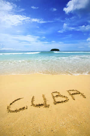在熱帶沙灘的沙上寫著「CUBA」，有藍綠色的水和遠處的小島。 — Vivo Pad SE 壁紙