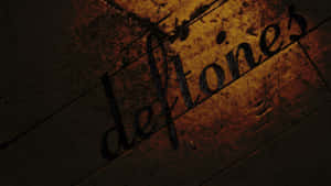 溫暖燈光下經風化木材上的「deftones」刮痕文字。 — 金屬索尼克 壁紙