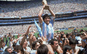 Diego Maradona 在球場上被歡呼的球迷包圍，手持世界盃獎盃。 — 運動 壁紙