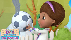 Doc McStuffins 在一個陽光明媚的庭院中抱著一個足球。 — 小醫師大玩偶 壁紙