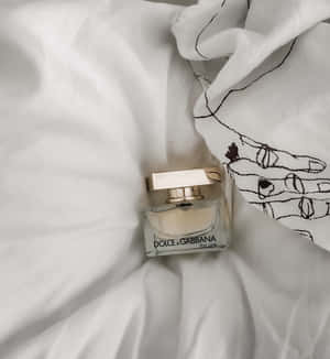 白色布料上的 Dolce & Gabbana 香水瓶與黑色手部圖案。 — 榮耀Magic V6 壁紙