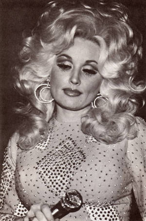 Dolly Parton 穿著閃亮服裝，戴著大圈耳環和麥克風表演。