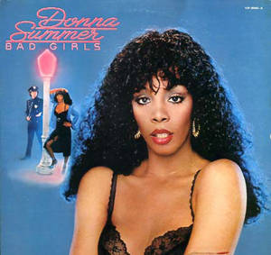Donna Summer 身穿黑色蕾絲，凝視觀眾，背後有一個警察和發光的街燈。 — 復古 壁紙