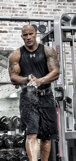 Dwayne Johnson 在磚牆健身房中拍打粉筆灰。