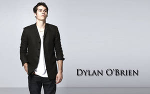 演員 Dylan O'Brien 身穿黑色西裝外套和白色T恤在工作室中擺姿勢。 — 狼少女 壁紙