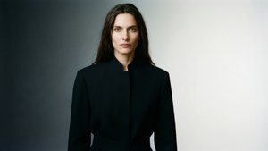 一位穿著黑色外套的女士在簡約的工作室環境中擺姿勢。