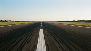 一條空蕩蕩的機場跑道在晴朗的藍天下延伸至遠方。