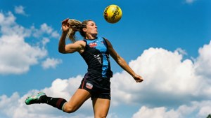 女運動員在藍天白雲下踢足球。